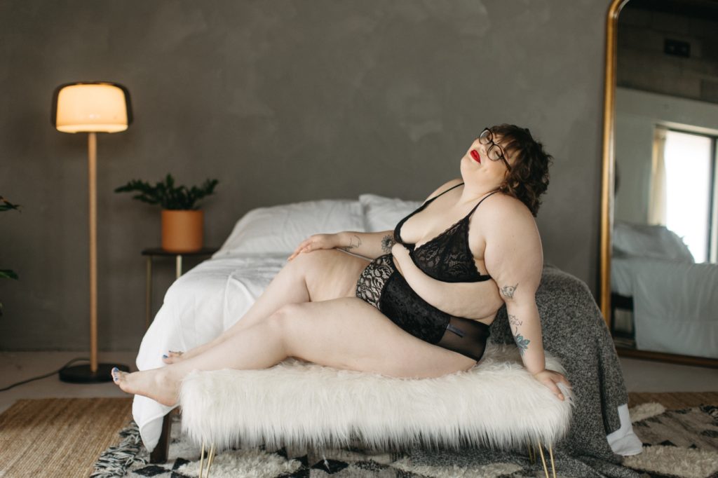Client lays across bed during good bodies vip winner boudoir session